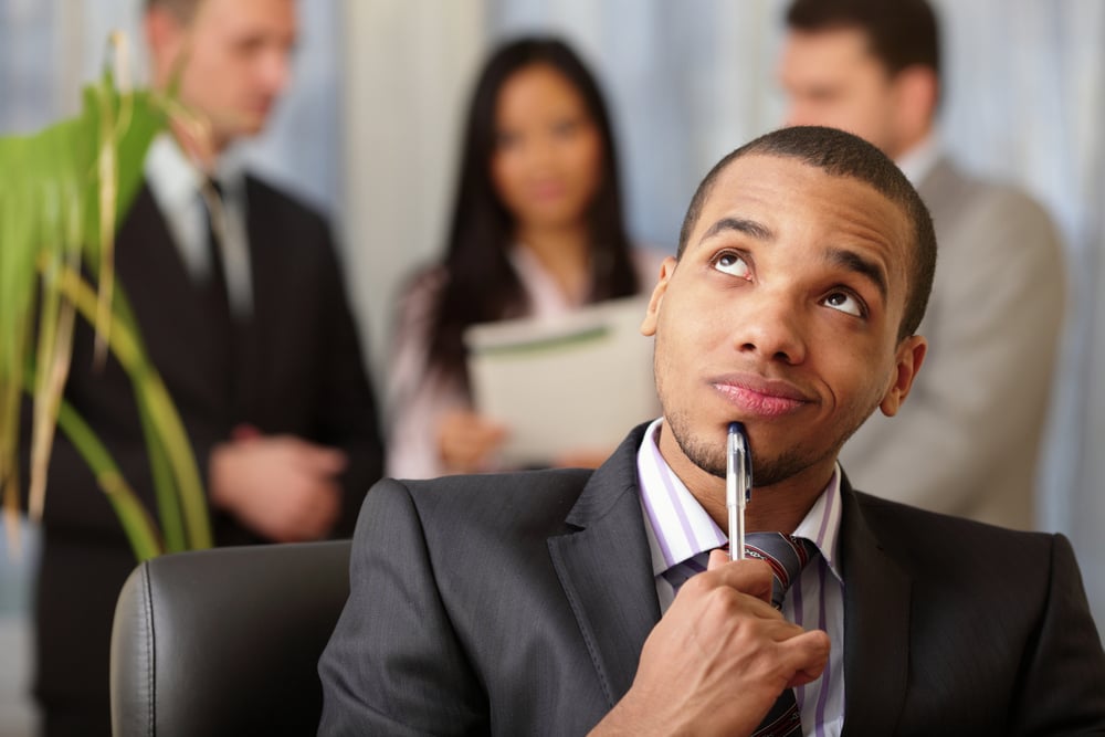 Pensive african-american businessman with his team working behind